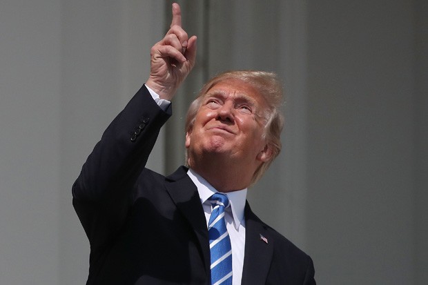 Donald Trump fazendo o que até uma criança de quatro anos saberia evitar: olhar diretamente para um eclipse solar (Foto: Mark Wilson/Getty Images)