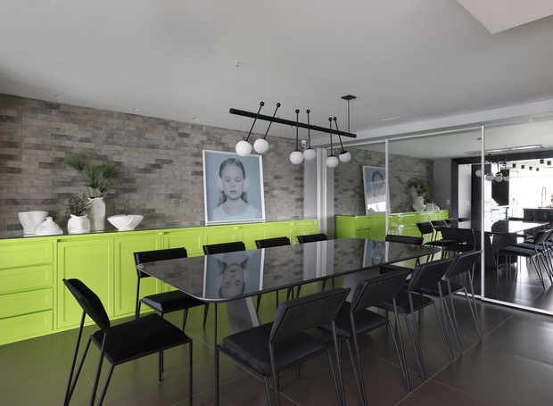 SALA DE JANTAR | O buffet projetado pelo escritório Inside foi produzido pela Saturno Marcenaria em laca verde néon, cor que acendeu a paleta cinza e preta. Tijolinhos na parede da Brick Studio.  (Foto: Mariana Orsi/Divulgação)