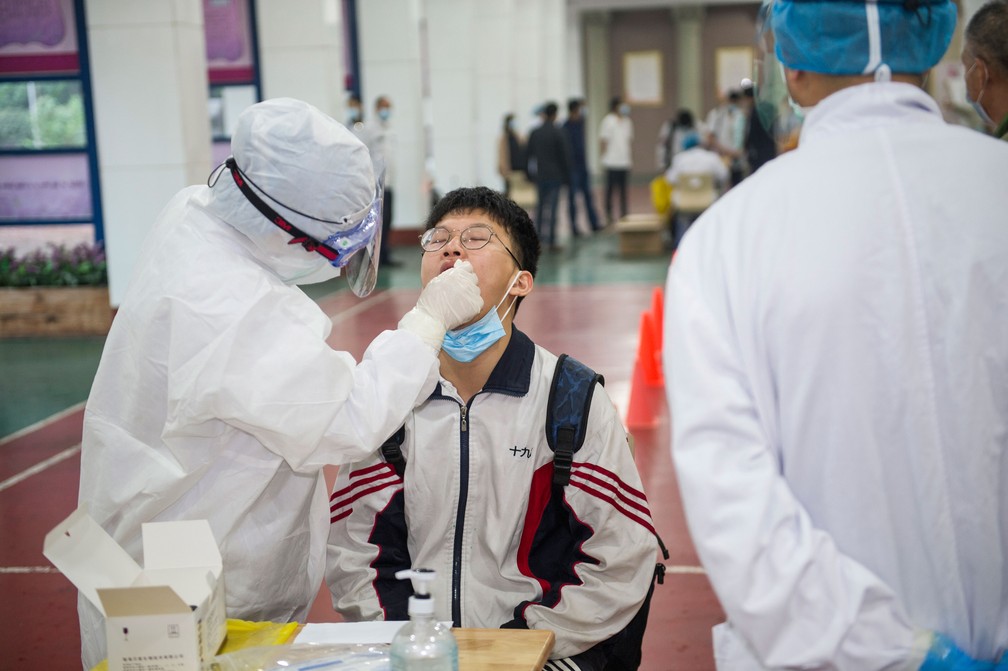 Profissional da saúde tira amostra com cotonete para fazer teste para o novo coronavírus de estudante na cidade de Wuhan, na região central da China, nesta quinta-feira (14)   — Foto: AFP