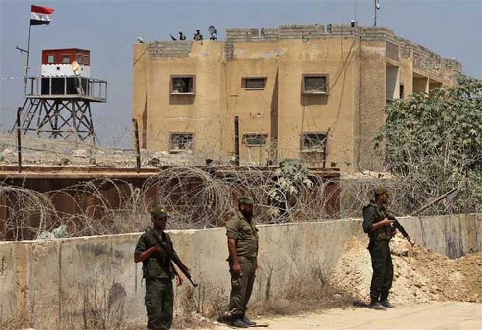  Em imagem de arquivo, integrantes das forças de segurança do Hamas (na frente) e soldados egípcios (atrás) fazem guarda na fronteira entre Egito e Faixa de Gaza, perto de Rafah. O Egito chamou de 'infiéis' os atiradores islâmicos que mataram 16 policiais perto da fronteira co (Foto: Reuters/Ibraheem Abu Mustafa)