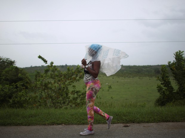 Moradora Guantánamo, em Cuba, se protege da chuva com saco plástico na passagem do furacão, na terça-feira (4) (Foto: Alexandre Meneghini/ Reuters)