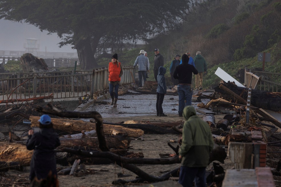 Moradores caminham em uma área danificada depois que tempestades de "rio atmosférico" atingiram o norte da Califórnia, na cidade de Aptos, EUA, em 5 de janeiro de 2023 — Foto: REUTERS/Carlos Barria