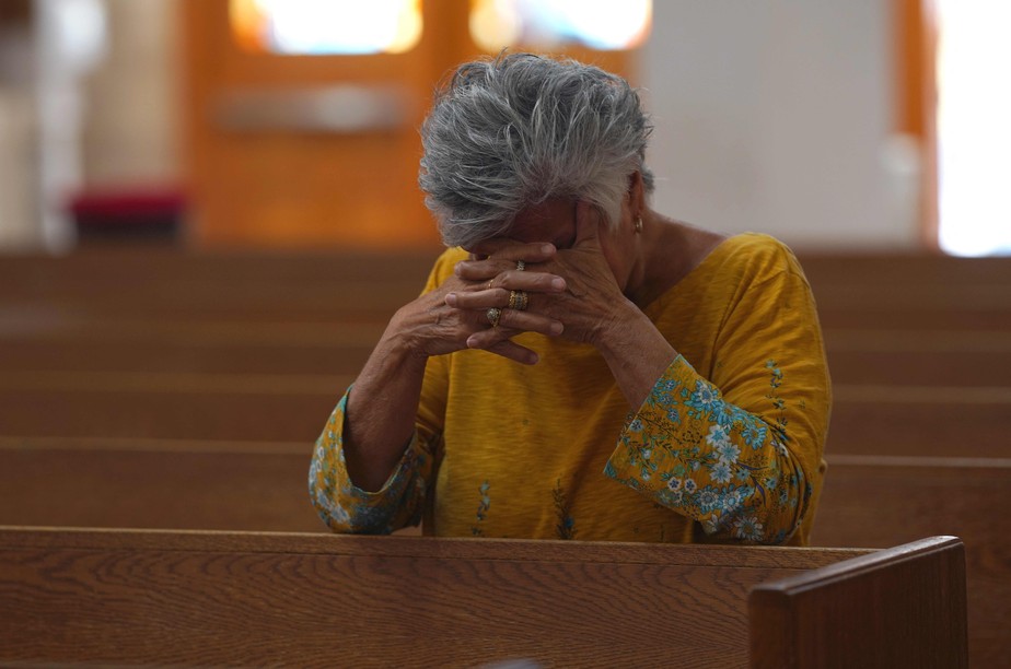 Mulher reza em homenagens às vítimas do ataque na Igreja Católica do Sagrado Coração, em Uvalde Texas