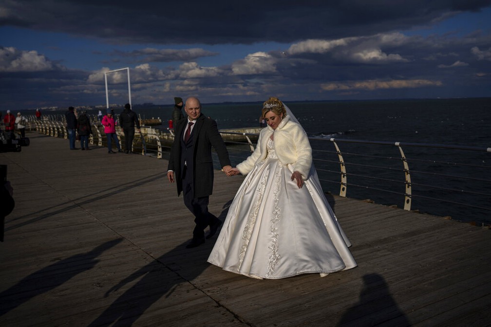 Os recm-casados ​​Alexandra Tabashnenko e Pavel Tabashnenko caminham aps cerimnia, s margens do Mar Negro, em Odessa, Ucrnia, na sexta-feira, 18 de fevereiro de 2022.  Foto: AP Foto/Emilio Morenatti