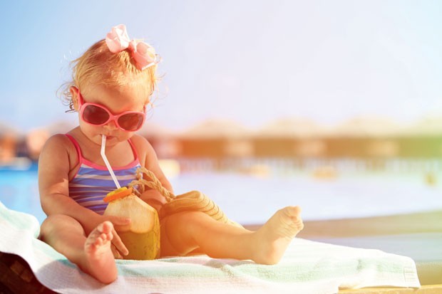 Bebê bebendo água de coco na praia (Foto: Thinkstock)