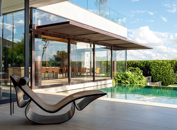 Cadeira de balanço Rio, de Oscar Niemeyer para a Etel. Um maciço de filodendros traz frescor à piscina (Foto: Keniche Santos / Divulgação)