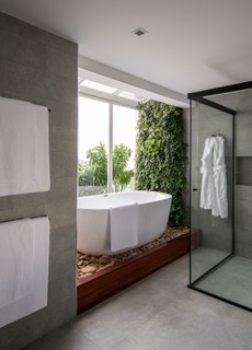 Na cobertura de 340 m², a suíte máster tem um amplo banheiro, com banheira e um jardim vertical. O boxe amplo tem duas duchas e fica de frente para a banheira. Projeto de Luana Mahfuz