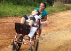Mãe empurra cadeira de rodas para filha poder ir à escola (Genival Moura/G1)