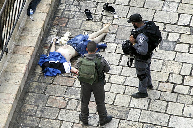 Policiais examinam corpo de palestino morto após esfaquear dois policiais no Portão de Damasco, em Jerusalém (Foto: Mahmoud Illean/AP)