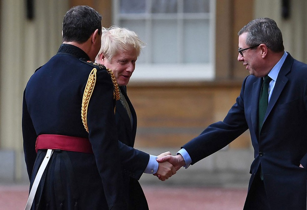 Após vitória em eleições gerais, premiê Boris Johnson é recebido pelo secretário particular da rainha Elizabeth II, Edward Young, ao chegar ao Palácio de Buckingham — Foto: Victoria Jones / AFP