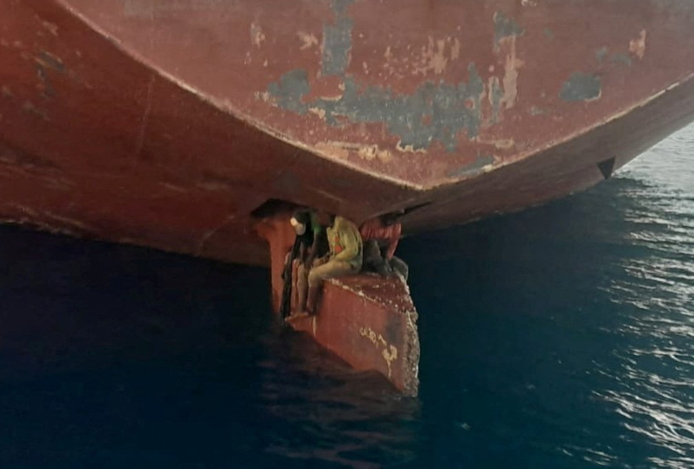 Três migrantes clandestinos são vistos na lâmina do leme do petroleiro Althini II depois de viajarem da Nigéria e antes de serem resgatados pela guarda costeira espanhola, próximo ao porto de Las Palma, nas Ilhas Canárias, na Espanha, em 28 de novembro de 2022 — Foto: Salvamento Maritimo via Reuters
