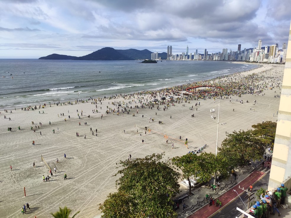 Fi&eacute;is caminham na areia alargada da Praia Central de Balne&aacute;rio Cambori&uacute; em evento religioso com a presen&ccedil;a de Bolsonaro &mdash; Foto: Ana Cristina Machado/NSC TV