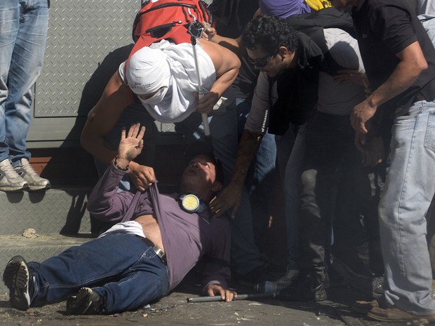 Pessoas ajudam um homem ferido durante protesto da oposição ao governo do presidente da Venezuela, Nicolas Maduro, em Caracas. (Foto: Juan Barreto/AFP)