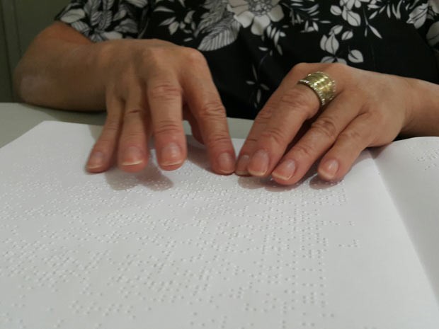 Muher com deficiência visual lê livro em Braille em biblioteca de Taguatinga, no Distrito Federal (Foto: Raquel Morais/G1)