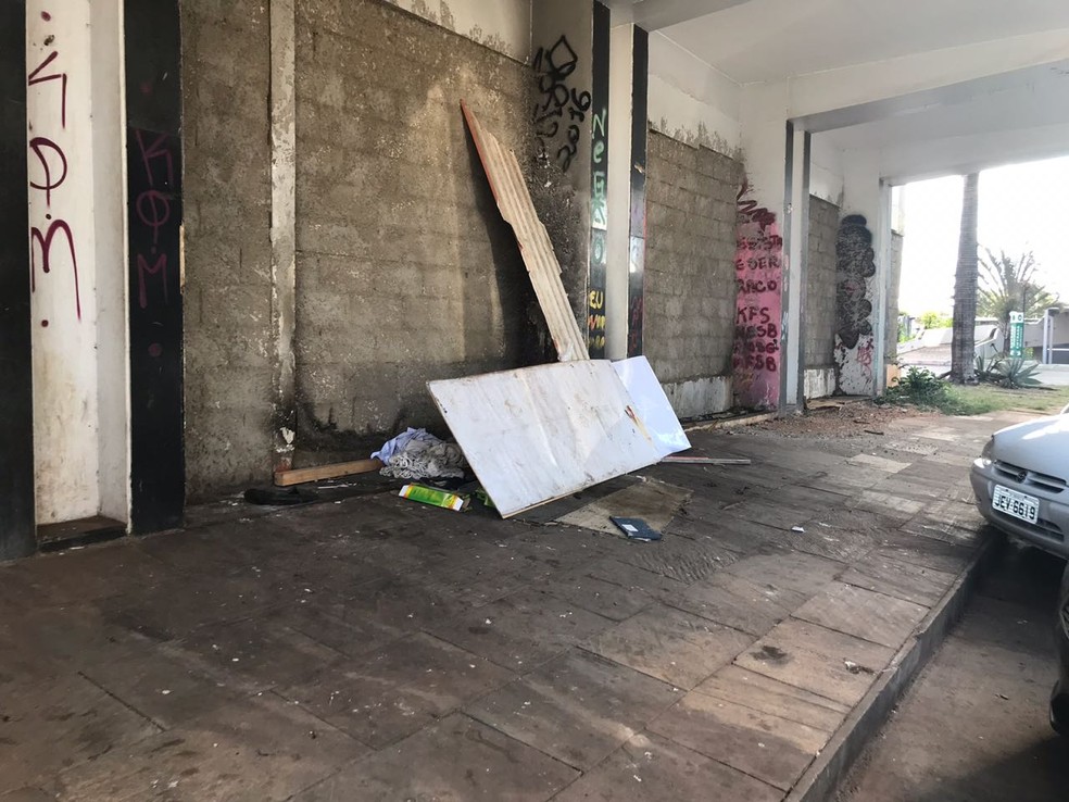 Muro de concreto fecha acesso ao Torre Palace; no detalhe, cama improvisada é coberta por tapumes (Foto: Marília Marques/G1)