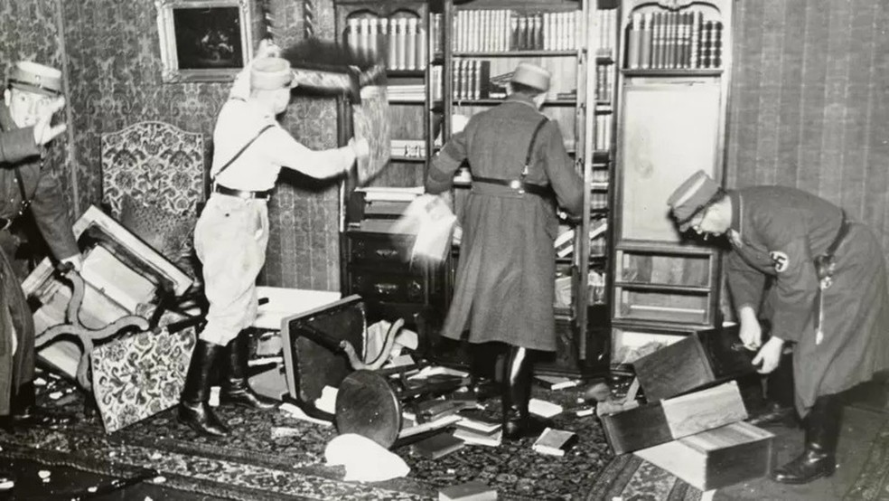 Oficiais nazistas derrubando livros de uma estante — Foto: YAD VASHEM PHOTO ARCHIVE via BBC