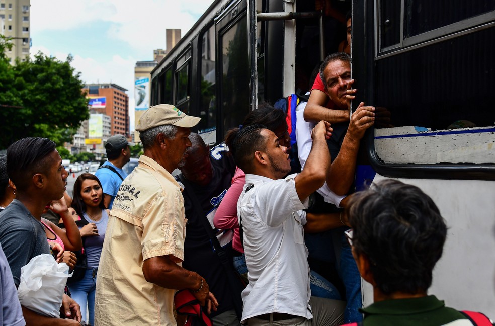 Pessoas se aglomeram para entrar em ônibus em Caracas nesta quinta-feira (30) depois que apagão interrompeu serviço de metrô na capital (Foto: Ronaldo Schemidt/ AFP)