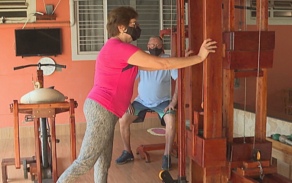 Com apoio da esposa, o casal se exercita em casa utilizando academia feita de madeira, em Goiânia — Foto: Reprodução/TV Anhanguera
