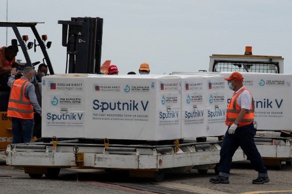 Funcionários do aeroporto venezuelano colocam em um caminhão refrigerado pacotes contendo 100.000 doses da vacina russa Sputnik V contra o vírus COVID-19 no aeroporto internacional Simon Bolivar em La Guaria, Venezuela, em 13 de fevereiro de 2021 — Foto: Yuri CORTEZ / AFP