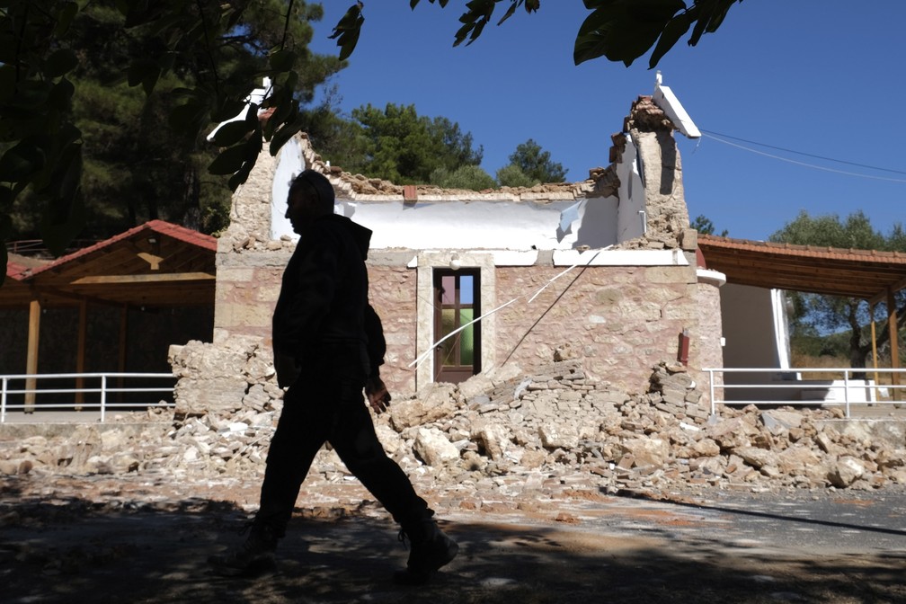 Homem caminha ao lado de capela ortodoxa grega danificada na vila de Arcalochori, na ilha de Creta, após forte terremoto no sul da Grécia em 27 de setembro de 2021 — Foto: Harry Nikos/AP