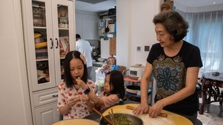 Sun Yang, do Glamma Beijing, em casa, prepara uma refeição ao lado das netas — Foto: Gilles Sabrié/NYT