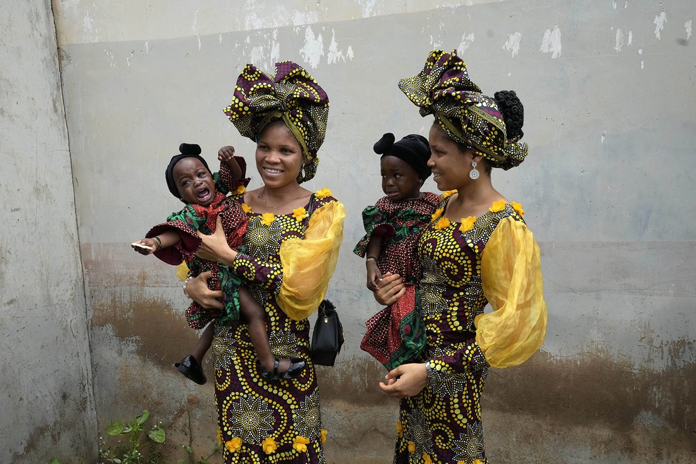 Oladapo Taiwo e Oladapo Kehinde, de 21 anos, posam com bebês gêmeas da mesma família enquanto participam do 12º festival de gêmeos de Igbo-Ora. A cidade no sudoeste da Nigéria celebra anualmente a alta incidência de gêmeos entre seus habitantes — Foto: Sunday Alamba/AP