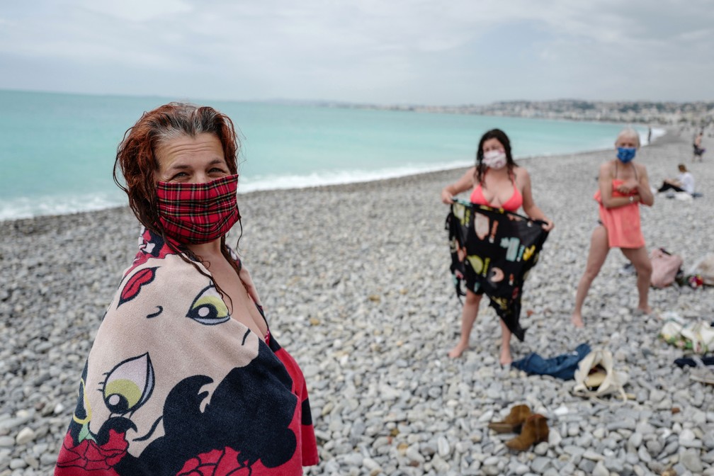 Mulheres usam máscaras protetoras após um mergulho em uma praia do Mediterrâneo em Nice, no sul da França, neste sábado (16)  — Foto: Valery Hache / AFP