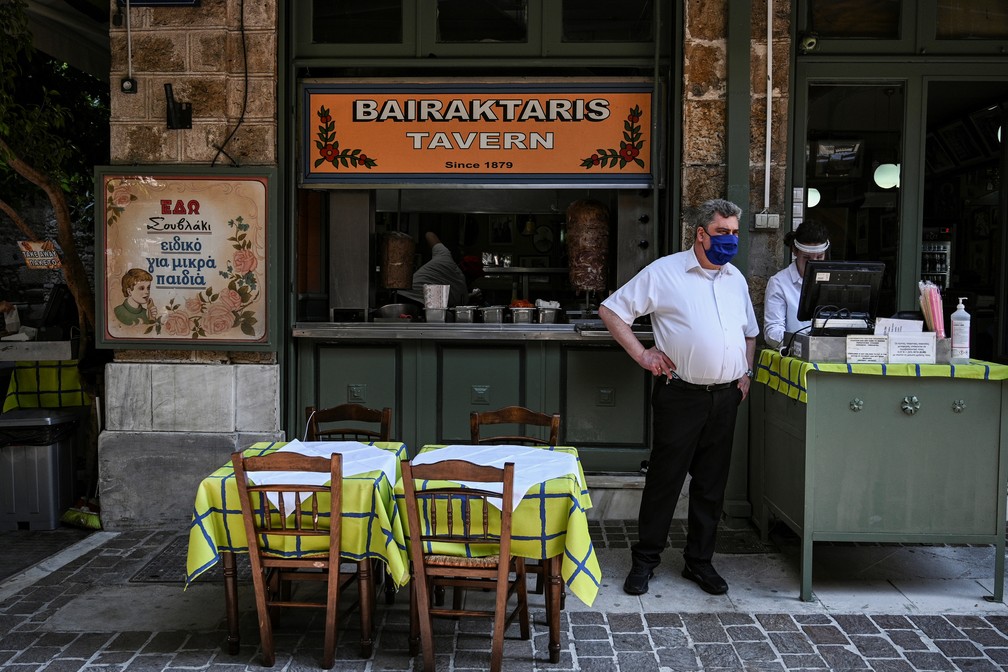 Taverna reaberta em Atenas, na Grécia, tem funcionários usando máscaras — Foto: Aris Messinis/AFP