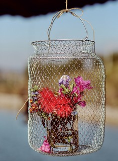 O samburá pendurado recebeu um vasinho de flores. Boa pedida para festas ao ar livre