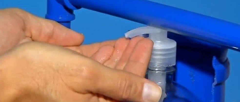 Pessoa usa dispensador de álcool em gel para higienizar as mãos e evitar contaminação pelo novo coronavírus — Foto: TV Globo/Reprodução