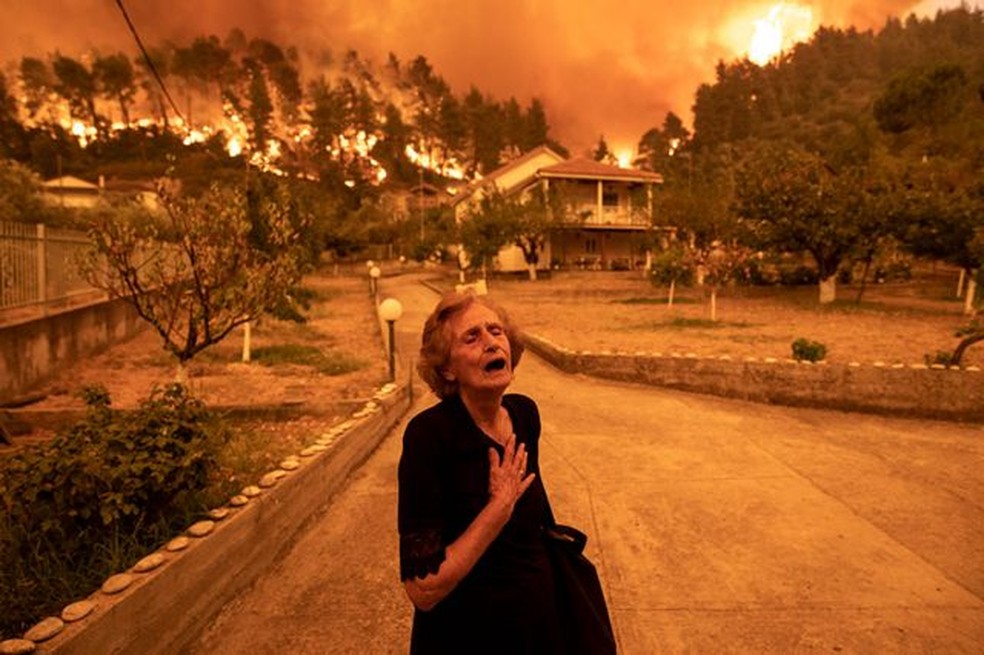 Uma idosa grita quando um incêndio se aproxima de sua casa na vila de Gouves, na ilha de Evia, Grécia, em 8 de agosto de 2021 — Foto: Konstantinos Tsakalidis para Bloomberg News