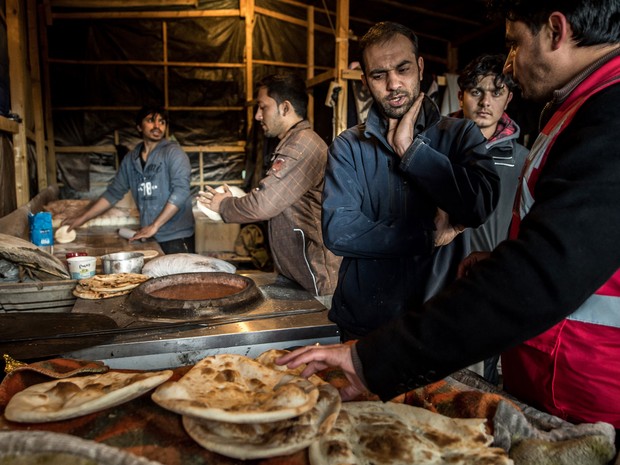 Migrantes cozinham no campo de refugiados ‘A selva’, em Calais, na quinta (14) (Foto: AFP Photo/Philippe Huguen)