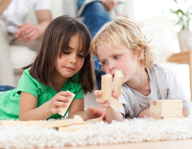 Menino e menina brincando juntos no chão (Foto: Shutterstock)
