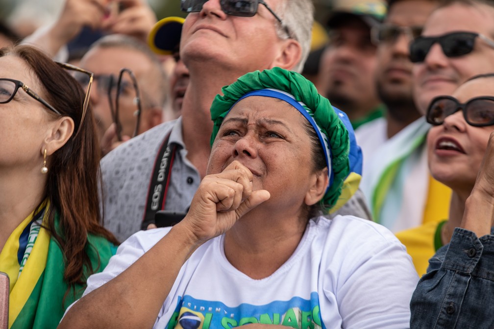 Mulher se emociona na Praça dos Três Poderes durante transmissão da sessão solene de posse em um telão — Foto: Fábio Tito/G1