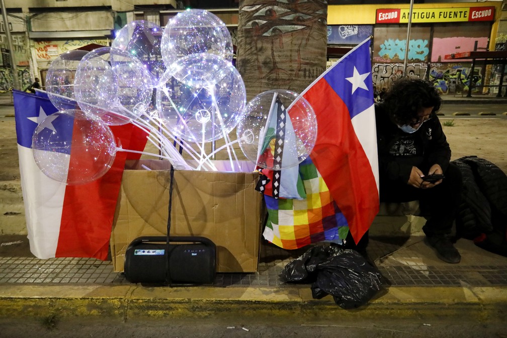 Um defensor da nova Constituição senta-se na calçada enquanto ouve os resultados parciais do plebiscito. — Foto: AP Photo/Cristobal Escobar