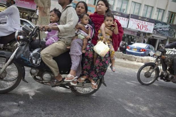 Em julho de 2011, um motociclista foi flagrado carregando outras cinco pessoas de sua família em uma moto na cidade de Karachi, no Paquistão. Entre os seis ocupantes havia dois bebês.  (Foto: Behrouz Mehri/AFP)