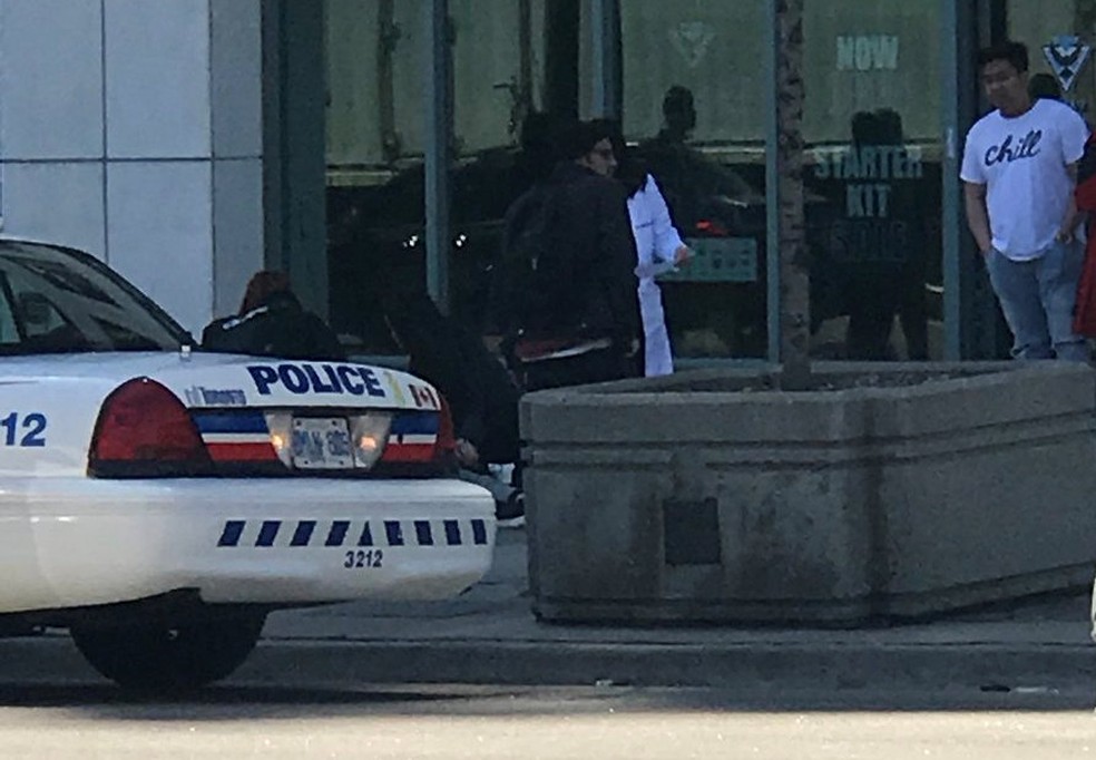 Uma vítima é socorrida por pedestres depois que uma van bateu em várias pessoas em um cruzamento em Toronto, no Canadá (Foto: Reuters)