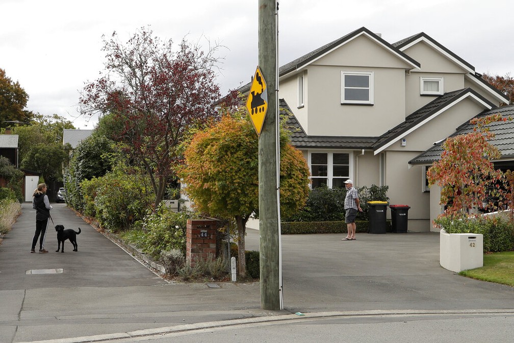 Vizinhos conversam à distância em um subúrbio no centro de Christchurch, Nova Zelândia, no sábado (28), país tem isolamento para evitar dispersão da Covid-19 — Foto: Mark Baker/AP