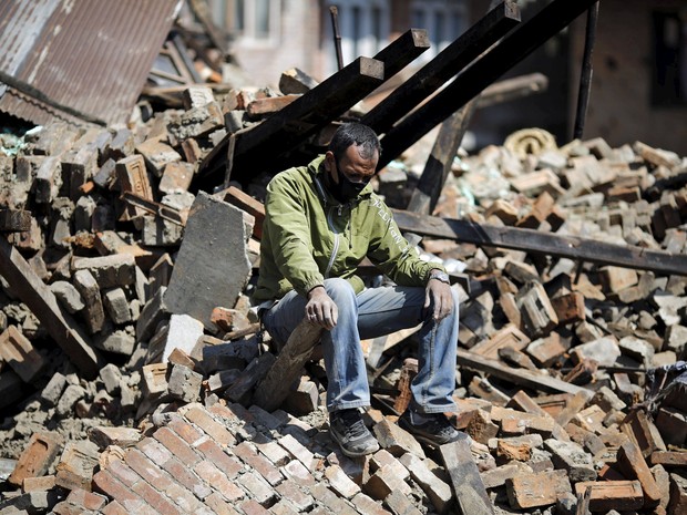Um homem senta-se sobre os escombros de sua casa danificada após o terremoto de sábado, em Bhaktapur (Foto: REUTERS/Adnan Abidi)