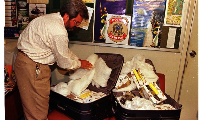 Agente da Polícia Federal com as malas e a droga achadas em avião da FAB, em 1999