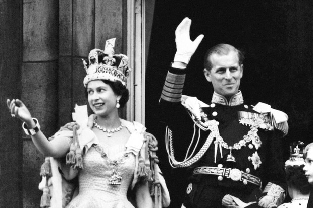 Queen Elizabeth II wearing the Imperial State Crown and the Duke of Edinburgh in uniform of Admiral of the Fleet wave from the balcony to the onlooking crowds around the gates of Buckingham Palace after the Coronation.   (Photo by PA Images via Getty Imag (Foto: PA Images via Getty Images)
