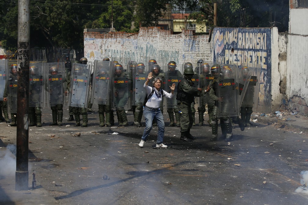Um manifestante tenta deter a violência ao se apresentar diante de soldados em Ureña, na fronteira entre a Venezuela e a Colômbia — Foto: Fernando Llano/AP