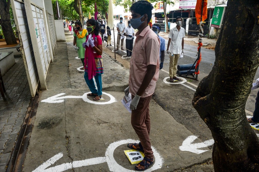 Jovens ficam em fila com marcas de distanciamento social no chão antes de entrar em um centro de exames de admissão para ingresso nas principais faculdades de medicina do país, em Chennai, no estado de Tamil Nadu, na Índia, em 13 de setembro de 2020. — Foto: Arun SANKAR / AFP