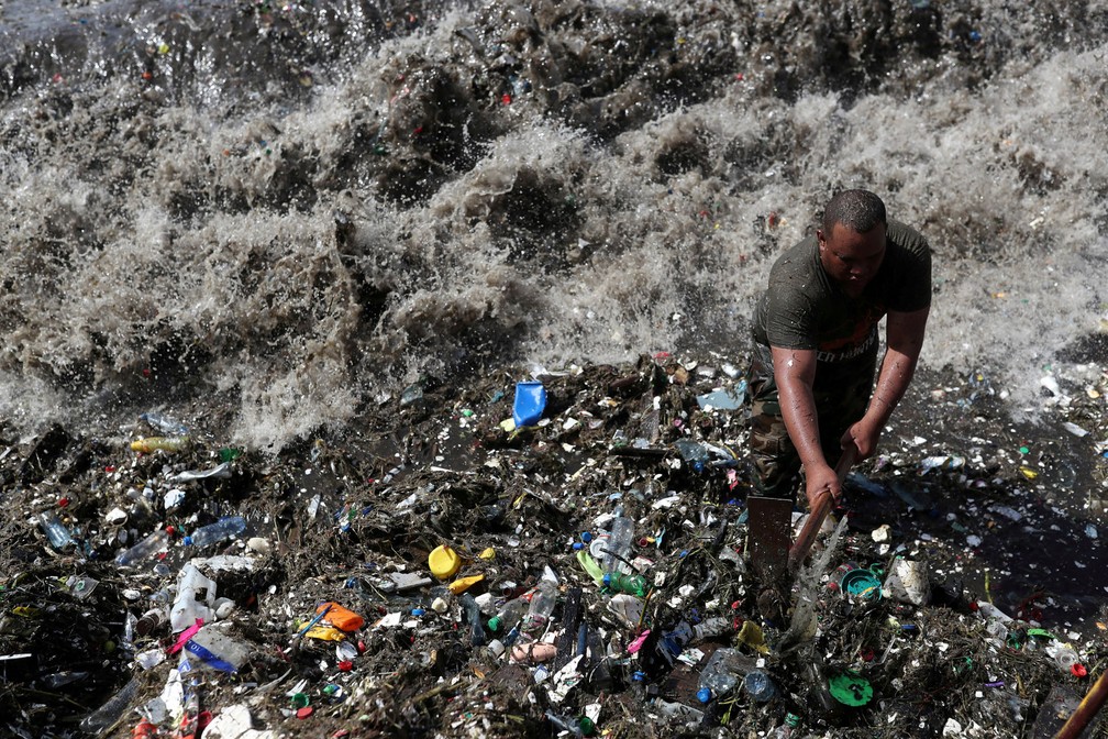 Soldado limpa as margens da praia de Montesinos, que é vista coberta de plástico e outros destroços, em Santo Domingo, República Dominicana (Foto: Ricardo Rojas/Reuters)