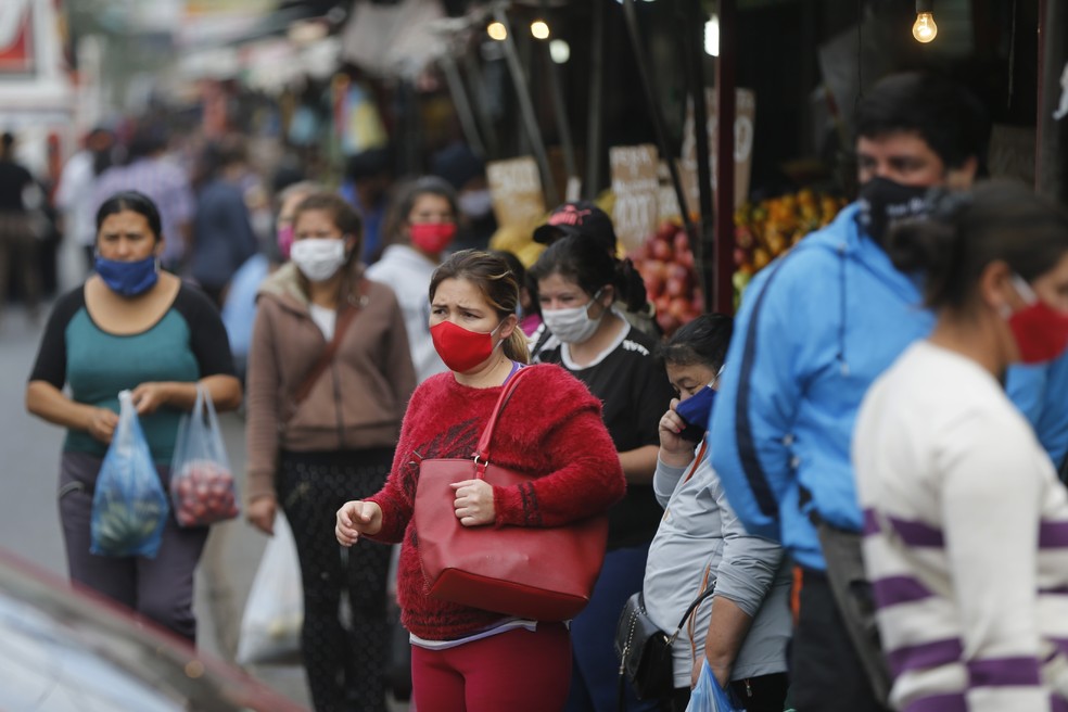 Com máscaras, paraguaios esperam ônibus no mercado de San Lorenzo, no Paraguai, durante a pandemia do novo coronavírus (COVID-19), em 27 de julho de 2020 — Foto: Jorge Saenz/AP