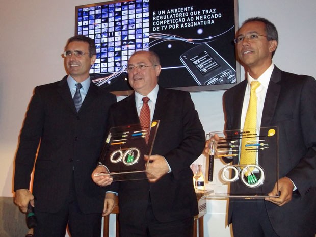 Valim, à esquerda, entrega a Paulo Bernardo e a Mauro Rangel uma placa de acrílico simulando com um circuito de fibra ótica (Foto: Lilian Quaino/G1)