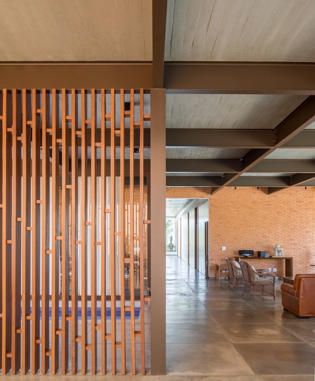 Painel vazado de madeira da Criarte ajuda a delimitar espaços integrados nessa casa térrea de Brasília. Pelo corredor se dá o acesso aos quartos da residência (Foto: Haruo Mikami)
