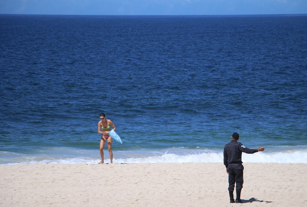 PM aborda banhista para que deixe praia. Decreto proíbe cidadãos de frequentar praias, para evitar aglomerações — Foto: José Raphael Bêrredo/G1 Rio