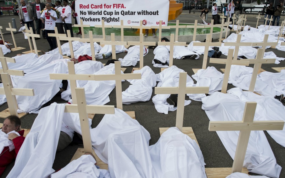 Ativistas colocam cruzes em frente à sede da Fifa na Suíça em protesto por direitos trabalhistas na construção de estádios para a Copa do Mundo do Catar. Entidade elege nesta sexta-feira (29) seu próximo presidente.  — Foto: Ennio Leanza/Keystone via AP