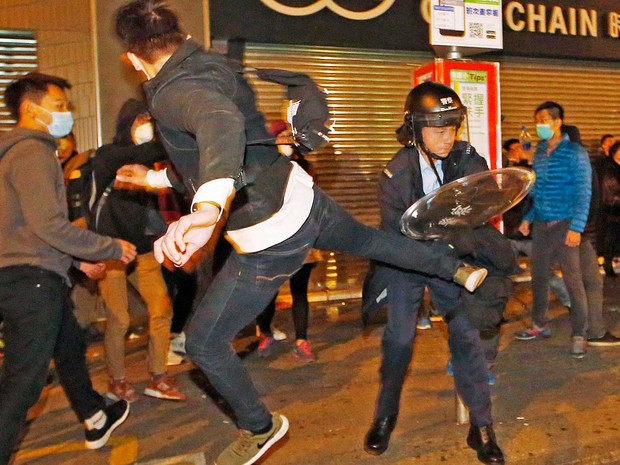 Manifestante salta para chutar um policial em Hong Kong (Foto: Kin Cheung / AP Photo)